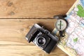 An orientation compass, an old camera and a geographic map rest on a wooden table with copy space for your text Royalty Free Stock Photo