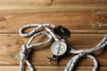 An orientation compass and a sailing rope rest on a wooden table with copy space for your text Royalty Free Stock Photo