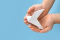 Origami art. Child holding paper bird on light blue background, top view. Space for text Royalty Free Stock Photo