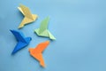 Origami art. Colorful handmade paper birds on light blue background, flat lay. Space for text Royalty Free Stock Photo