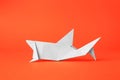 Origami art. Handmade white paper shark on orange background