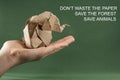 Origami baby elephant Kraft paper on a green background on the hand, the concept of saving paper and forests, save paper, save the Royalty Free Stock Photo