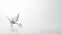 An origami bird with a flower on a white background. The bird is white and stands on two legs. The flower is yellow and