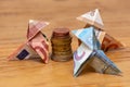 Origami birds made of 10, 20 and 50 euro bank notes around a stack of euro coins