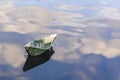 Origami boat built of one hundred dollar bill. paper boat from a hundred dollar bill in blue water. copy space. Concept: Royalty Free Stock Photo