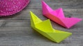 Origami, colorful boats and pink hat on wooden background, hobby