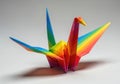 An origami crane folded from bright rainbow-colored paper, casting a shadow on a white background Royalty Free Stock Photo