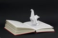 Origami dinosaur coming out of a book