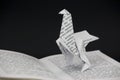 Origami dinosaur coming out of a book