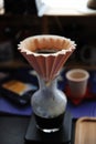 Origami filter dripping coffee into a glass carafe. Electronic scale. Alternative manual brewing