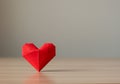 Origami heart made from red paper displayed on a flat wooden surface. The paper\'s Royalty Free Stock Photo