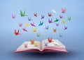 Origami made colorful paper bird flying over open book Royalty Free Stock Photo