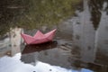 Origami paper boat in a puddle of rainwater. The photo illustrates cloudy weather: rain, flood