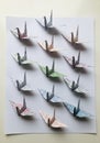 Origami paper cranes in various colors arranged in rows on a white background. Each crane is folded Royalty Free Stock Photo