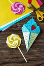 Origami paper ice cream and lollipop on a wooden table.