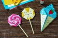 Origami paper ice cream and lollipop on a wooden table.