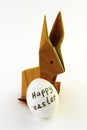 Origami rabbit from orange colored paper. Easter bunny and white chicken egg with the inscription Happy Easter on a white Royalty Free Stock Photo