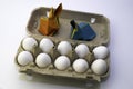 Origami rabbits from colored paper. Easter hares and white chicken eggs in a box