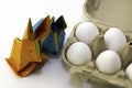 Origami rabbits from colored paper. Easter hares and white chicken eggs in a box Royalty Free Stock Photo