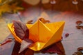 Origami yellow paper boat in a rain puddle between fallen autumn leaves, water circles, fall weather and mood Royalty Free Stock Photo