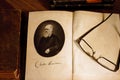 The origin of species by Charles Darwin opened on first page with glasses on the second page.