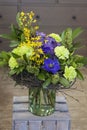 The original bouquet of blue anemones, carnations, forsythia stands in a glass vase