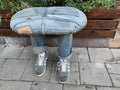 An original chair in the shape of legs. Creative sitting in nature - jeans and sneakers. Street stool next to the sidewalk. Turkey