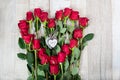 Original festive arrangement of long red roses - El Toro variety in the shape of a heart with wooden hearts in the center on a