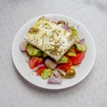 Original feta cheese in Greek salad with tomatoes cucumbers, olives and onions plate Royalty Free Stock Photo