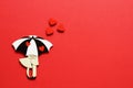 Stylized stylish vintage figurine of lovers under bright umbrella with red hearts on red background. Minimal background for day of