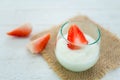 Original flavor yogurt with fresh strawberry in clear glass on white wood background