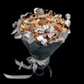 Original gift homemade in the form of a bouquet of different varieties of nuts and decorated with silver leaves isolated on black