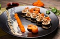 Original Japanese rolls in restaurant serving with fish slices, caviar, sesame seeds. Front detailed view. Dish recipe.
