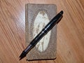 An original leather notebook for writing and a ballpoint pen on the surface of a wooden table. Place for text. Closeup.