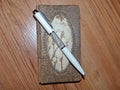 An original leather notebook for writing and a ballpoint pen on the surface of a wooden table. Place for text. Closeup.