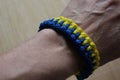 The original macrame bracelet adorns the hand. The classic combination of yellow and blue colors gives it brightness