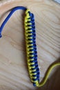 The original macrame bracelet adorns the hand. The classic combination of yellow and blue colors gives it brightness