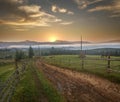 Original rural settlement high in mountains, farm with horses, road leading to hills in morning fog on background of magnificent Royalty Free Stock Photo