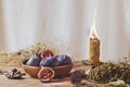 An original still life of Russia with the fire of a wax candle. A wax candle with blue figs in a wooden plate, candle fire, dried