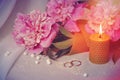 An original still life of Russia with the fire of a wax candle. Wedding candle fire candles in pink flowers, wedding rings.