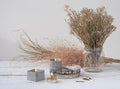 An original still life in the style of wabi-sabi with candles. Candles in concrete candlesticks, restrained dry flowers.