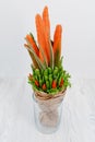 An original vegetable bouquet consisting of carrots, pea pods, lettuce leaves, red pepper and aloe is stand in a glass vase as a s