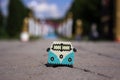 The original white turquoise beaded brooch in the form of a vintage van stands on the alley against the backdrop of columns and