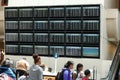 People rushing to get to their flights at a busy international airport in front of the arrivals and departure board