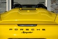 The rearend of a yellow Porsche Spyder sitting in front of a home