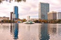 Colorful vintage fountain , business buildings, swan boats and autumn trees at Lake Eola Park in Orlando Downtown area 1 Royalty Free Stock Photo