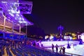 Colorful view of stadium, with ice rink, holiday trees and snowman. People leave when the show is over in International Drive area