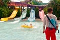 Man enjoying water attraction on yellow waterpark tube. Lifeguard looking pool at Aquatica Par