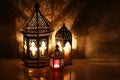 Ornamental Arabic lanterns with burning candles on table glowing at night. Festive greeting card, invitation for Muslim