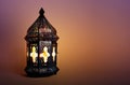 Ornamental dark Moroccan, Arabic lantern on the table. Burning candle in the night. Greeting card for Muslim community